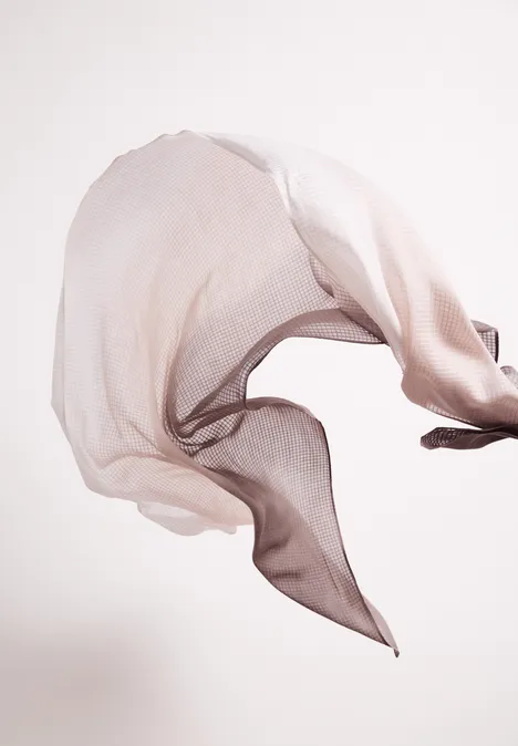 Leichter, transparenter Stoff, der in der Luft schwebt und geschwungene Formen bildet.