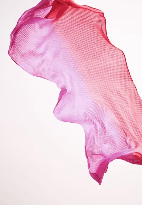 Leichter, rosafarbener Chiffon-Stoff, der in sich wirbelt vor hellem Hintergrund.