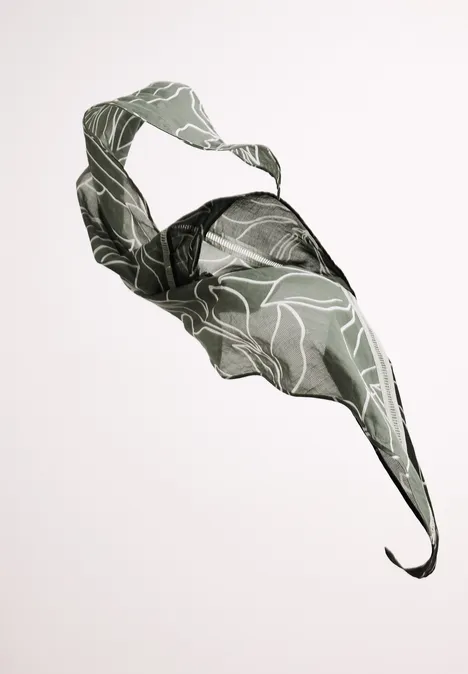 Leichter grün gemusterter Stoff in geschwungener Schwebeform vor hellem Hintergrund