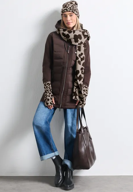 Femme en doudoune marron, écharpe imprimé animal, jean large, bottines noires et grand sac marron.