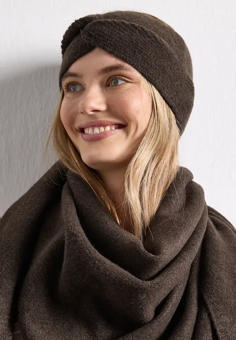 Feinstrick Stirnband in Unifarbe auburn brown mel. Frau mit braunem Turban-Stirnband und passendem Schal, lächelnd, blondes Haar, vor hellem Hintergrund