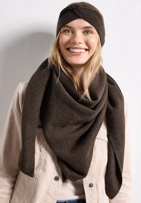 Feinstrick Stirnband in Unifarbe auburn brown mel. Junge Frau mit braunem Strickhut und passendem Dreiecksschal lächelt vor weißem Hintergrund.