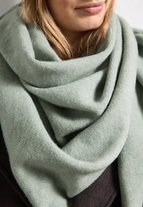 Feinstrick Dreieckstuch in Unifarbe eucalyptus green mel. Nahaufnahme einer Frau mit einem weichen, salbeigrünen Schal, der lässig um den Hals drapiert ist.