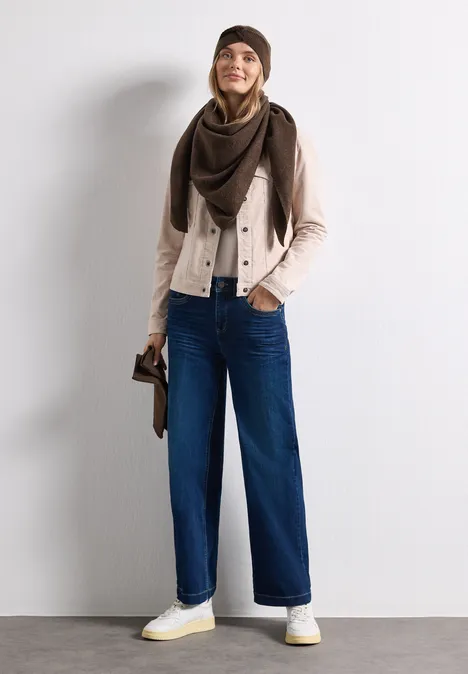 Feinstrick Dreieckstuch in Unifarbe auburn brown mel. Eine junge Frau in Mütze, Schal, heller Jacke, weiten Jeans und weißen Sneakers lächelt.