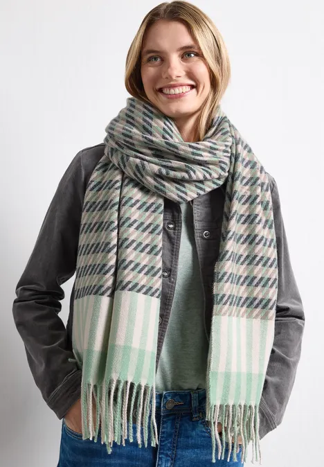 Lächelnde Frau mit kariertem Schal und Lederjacke, moderner Winterlook.