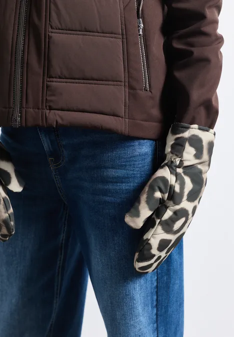 Personne porte une veste marron, un jean bleu et des moufles blanches à motifs tachetés noirs.