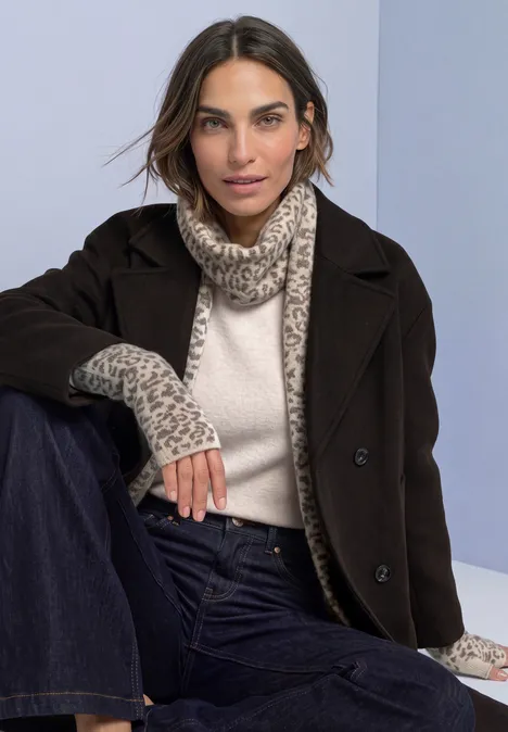 Jacquard Armwärmer mit Leo-Muster barley beige mel. Frau im dunkelbraunen Mantel, cremefarbenem Rollkragenpullover, Leopardschal und Jeans.