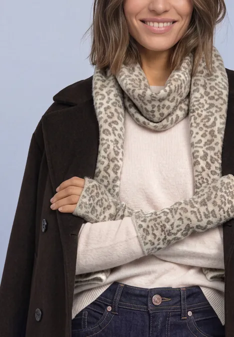 Jacquard Armwärmer mit Leo-Muster barley beige mel. Frau trägt braunen Mantel, beigen Pullover, gemusterten Schal und passende Stulpen in heller Farbpalette.
