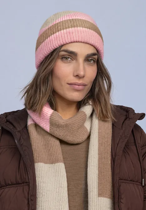 Frau in brauner Jacke mit pink-beiger gestreifter Strickmütze und passendem Schal.