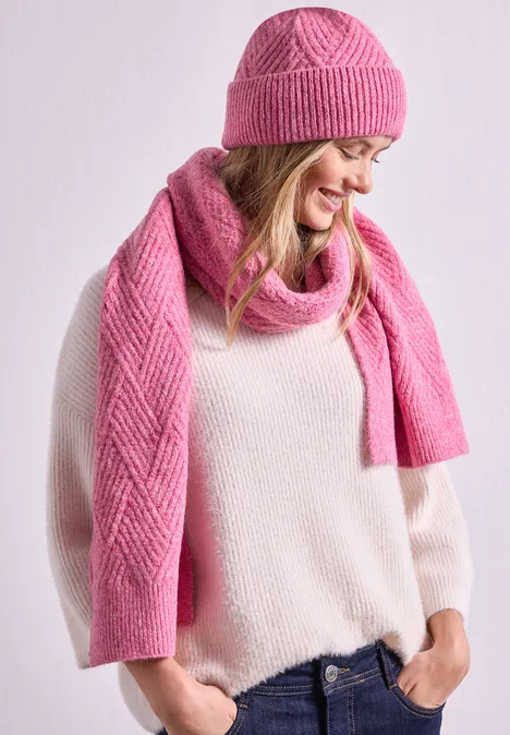 Frau mit rosa Strickmütze, passendem Schal und hellem Pullover