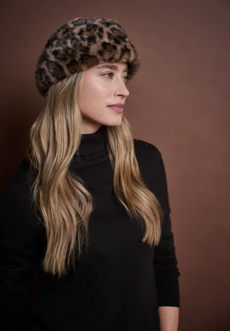 Beanie van imitatiebont met luipaardprint Black Frau mit langen blonden Haaren trägt einen Leopardenfellhut und schwarzen Rollkragenpulli vor braunem Hintergrund.