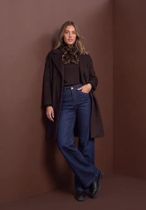 Stropdas van imitatiebont met luipaardprint Black Eine elegante Frau in braunem Mantel, schwarzem Oberteil und Jeans steht vor braunem Hintergrund.