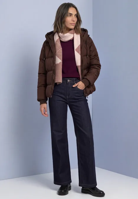 Longue écharpe à motif Argyle vintage blush mel. Frau in brauner Steppjacke, Bordeaux-Pullover, Schal und dunklen Jeans vor neutralem Hintergrund.