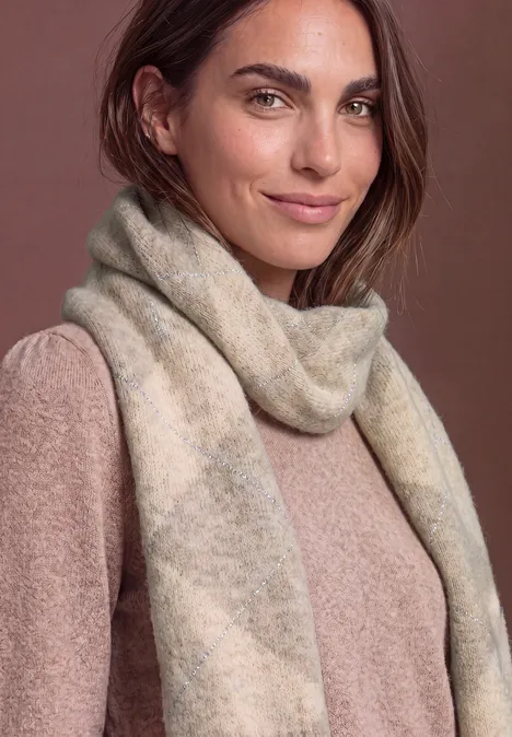 Longue écharpe à motif Argyle barley beige mel. Eine Frau trägt einen weichen, cremefarbenen Schal und einen passenden Pullover, warme neutrale Töne.