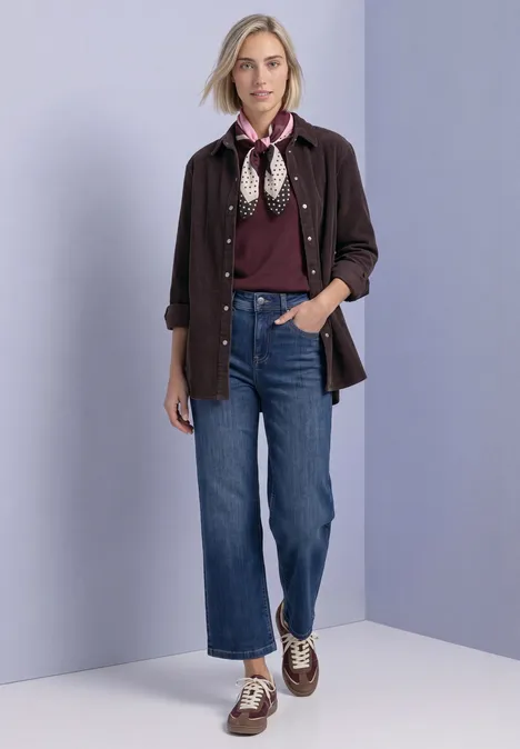 Doek met grafisch patroon rustic rouge Frau in lockerem Casual-Outfit: dunkelrote Bluse, dunkelbraune Hemdjacke, Jeans, Halstuch und Boots.