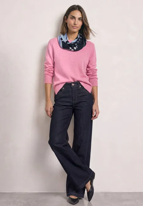 Loop-Schal mit floralem Muster indigo night Model mit rosa Pullover, weitem dunklem Jeans, blauem Halstuch und schwarzen Pumps vor hellem Hintergrund.