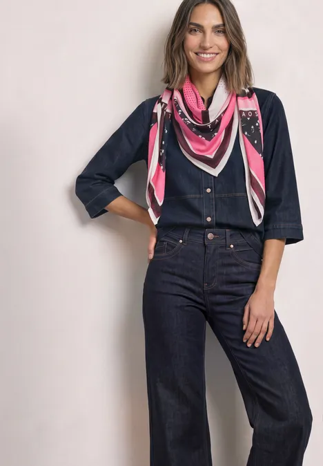 Quadratisches Tuch mit Grafikprint multicolor Frau in dunkelblauem Denim-Overall mit 3/4-Ärmeln und pinkem gemustertem Halstuch, lächelnd