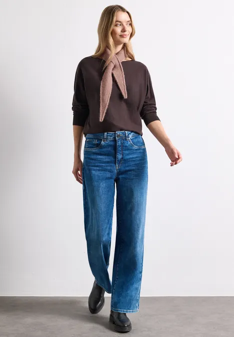 Mini-driehoekssjaal in effen kleur vintage blush mel. Vrouw in een bruine trui, een sjaal, wijde blauwe jeans en zwarte schoenen tegen een witte achtergrond.