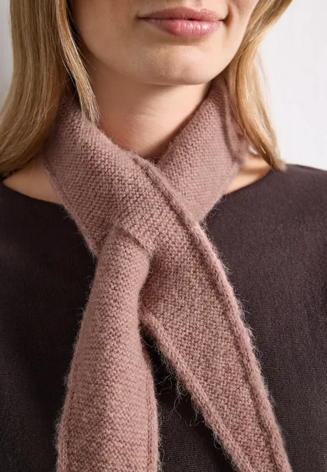 Mini-driehoekssjaal in effen kleur vintage blush mel. Een vrouw draagt een zachte, bruine gebreide sjaal die gekruist op de borst zit.