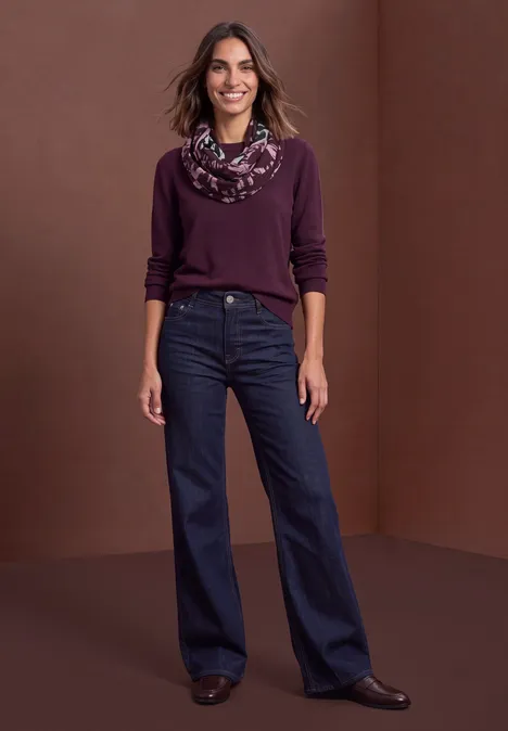 Loop-Schal mit Struktur und Print Black Eine Frau in lila Pullover, gemustertem Schal und dunklen Jeans steht vor braunem Hintergrund.