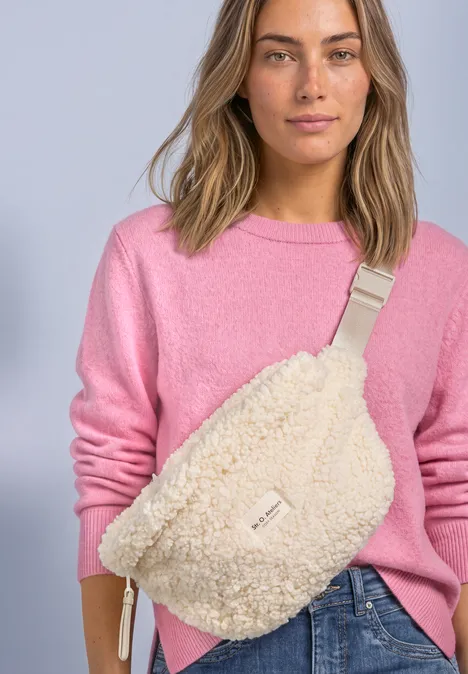 Teddy-Umhängetasche in Unifarbe barley beige Frau in pinkem Pullover trägt gemütliche Teddy-Muster Gürteltasche über Jeans.
