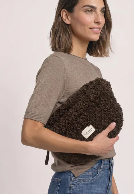Teddy-schoudertas in effen kleur auburn brown Vrouw in t-shirt en jeans houdt een zachte, bruine pluchentas tegen haar aan.