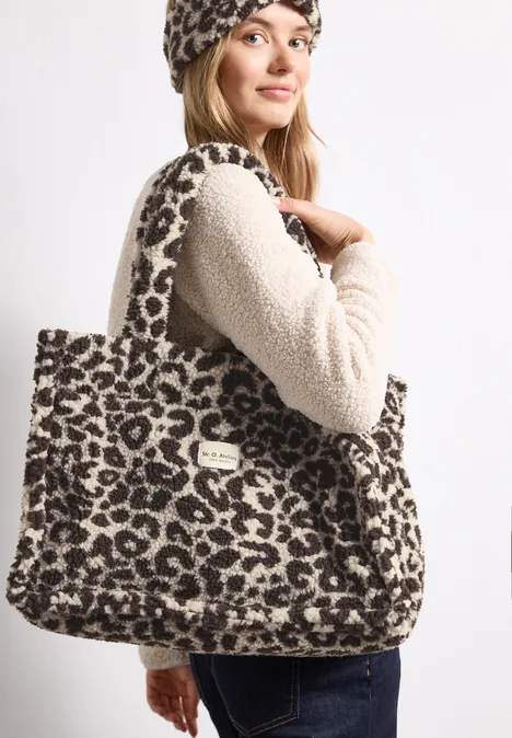 Teddy-Tragetasche mit Leo-Muster auburn brown Frau trägt flauschige Leoparden-Tasche und passendes Stirnband.
