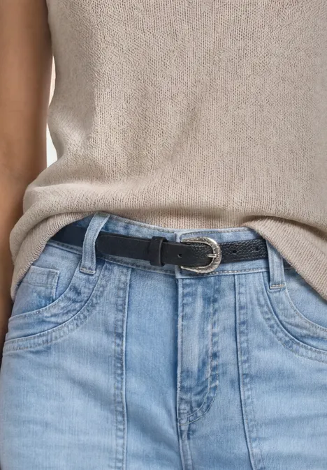 Smalle riem met decoratieve gesp Black Frau mit schulterfreiem beigen Top und schwarzem Gürtel vor hellem Hintergrund.