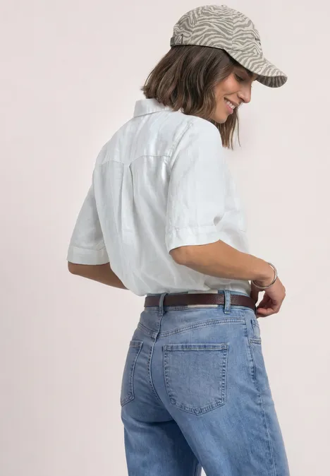 Smalle riem met decoratieve gesp rustic rouge Frau mit weißem Hemd, blauen Jeans und gestreifter Cap steht seitlich und lächelt.