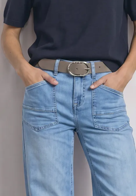 Gürtel mit dekorativer Schnalle Muddy Mocha Person mit blauer Jeans, breitem Gürtel und dunklem Oberteil, Hände in den Taschen