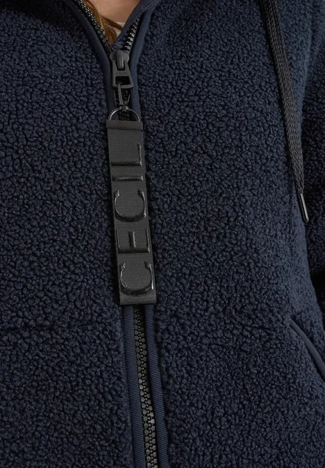 Nahaufnahme einer dunkelblauen Teddy-Fleecejacke mit Reißverschluss und Logo-Zipper-Patch.