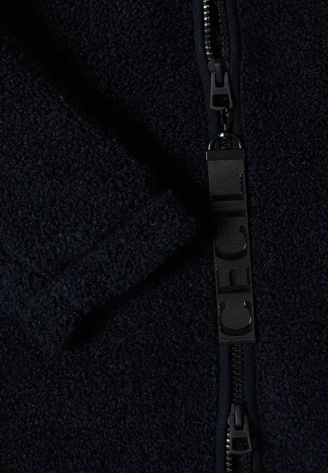 Nahaufnahme eines schwarzen Reißverschlusses an dunkelblauem Fleece-Stoff.