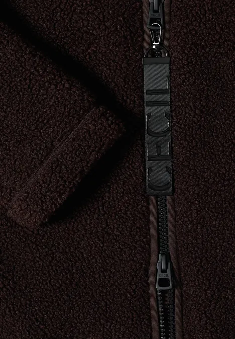 Nahaufnahme eines dunklen Fleece-Stoffes mit einem robusten Reißverschluss und Logo-Anhänger.