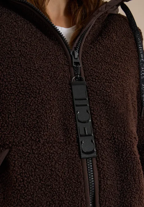 Nahaufnahme einer braunen Teddy-Fleecejacke mit auffälligem schwarzem Reissverschluss-Zipper