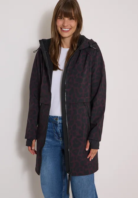 Softshell-jas met capuchon en luipaardprint berry red Frau trägt gemusterten, dunkelroten Mantel mit Kapuze, weißes T-Shirt und Jeans, lächelnd.