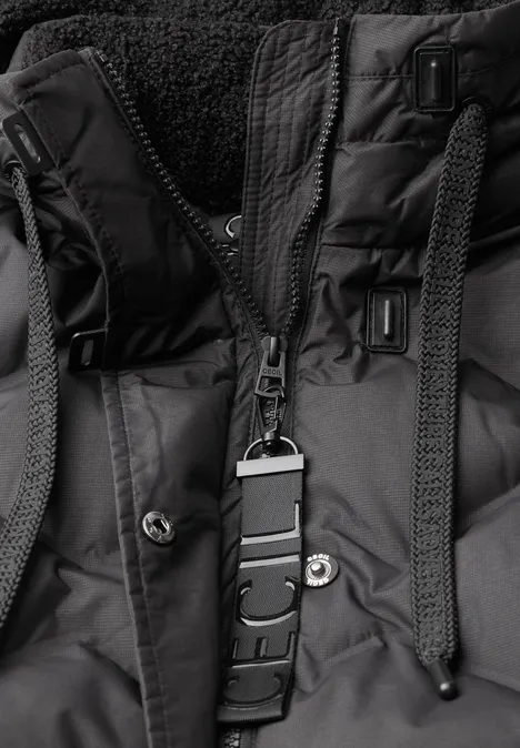 Gros plan d'une veste d'hiver noire avec fermeture éclair, boutons-pression, cordons et intérieur polaire.