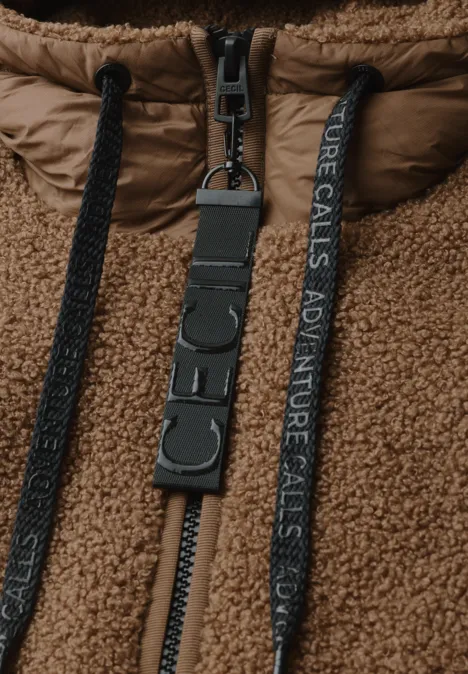 Veste en sherpa marron avec fermeture éclair, cordons noirs et sangle 'ADVENTURE CALLS' fixée à un anneau en D