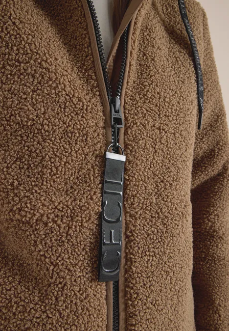 Gros plan sur une fermeture éclair en teddy marron avec tirette en cuir