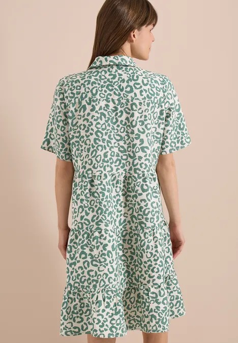 Vue de dos d’une femme portant une robe ample à manches courtes au motif léopard vert et blanc.