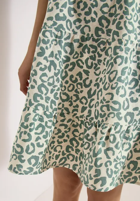 Gros plan d'une robe à imprimé léopard vert avec volant sur l'ourlet.