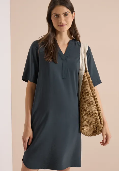 Knie-lange jurk met split in de hals palm breeze green Donkergrijze T-shirtjurk met V-hals en korte mouwen, gecombineerd met een gevlochten strooien tas.