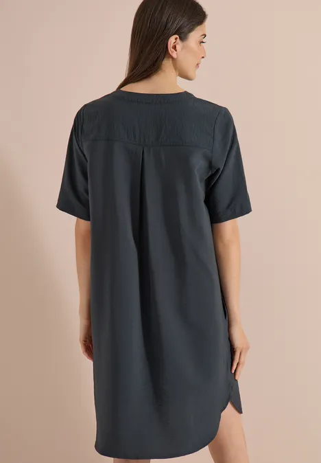 Knie-lange jurk met split in de hals palm breeze green Vrouw van achteren in losvallende, donkerkleurige halflange jurk met korte mouwen en rugdetail.