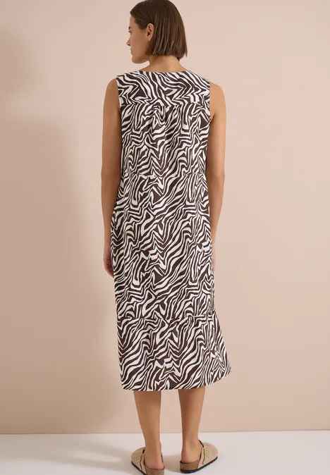 Femme vue de dos, robe midi sans manches à motif zèbre, chaussures plates.