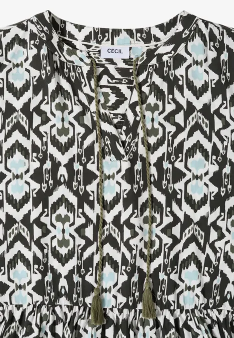 Ärmellose Bluse mit schwarz-weißem Ikat-Muster und Quasten am Ausschnitt.