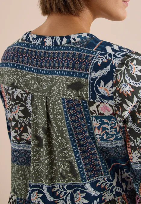 Rückansicht einer Bluse mit buntem Patchwork aus floralen und geometrischen Mustern in Blau und Grün.