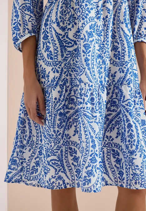 Weißes Sommerkleid mit blauem Paisley- und Blattmuster, leicht fallend.