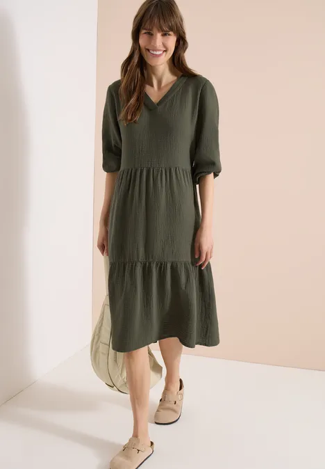Damen-Midikleid in Olivgrün mit V-Ausschnitt, halblangen Ärmeln und Stufenrock, lässig gestylt.