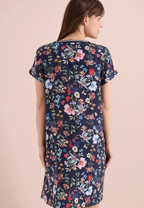 Frau von hinten in knielangem, dunkelblauem Kleid mit buntem Blumenmuster.