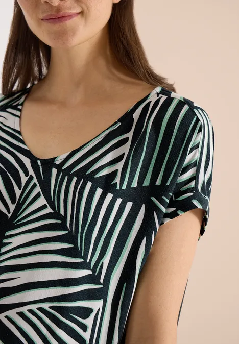 Frau in T-Shirt mit abstraktem, schwarz-weiß-grün gestreiftem Design.