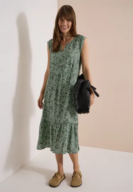 Midikleid mit Split Neck und Print khaki Frau trägt grünes, gemustertes Midikleid und hält eine schwarze Handtasche.